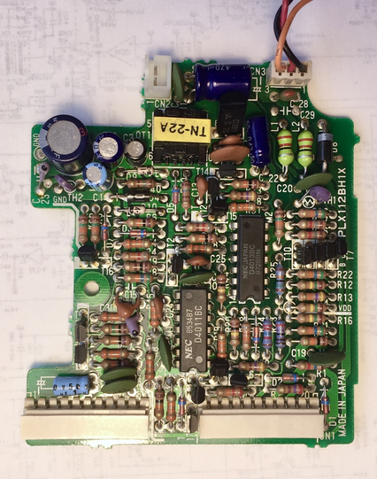 Close up view of the power supply board from the NEC PC-8201 laptop computer. Resistors, capacitors, and other electronic components are visible on the green printed circuit board.