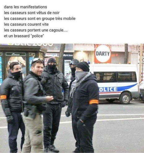 Dans une rue de Paris pendant une manif un groupe de 5 hommes vêtus de noirs, les visages masqués qui par une cagoule qui par un foulard deux d'entre eux portent un brassard de police orange En fond à droite un fourgon de police et au dessus de la photo le texte suivant dans les manifestations les casseurs sont vêtus de noir les casseurs sont en groupe très mobile les casseurs courent vite les casseurs portent une cagoule...et un brassard "police"