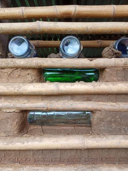 The same wall, but showing the top level of progress with a row of glass bottles waiting to be encased in the earthcrete mix.