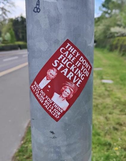 Red sticker on a pole featuring Charles & Camilla and the words "They don't care if you fucking starve.
Who do you think pays the bills for all those palaces?"