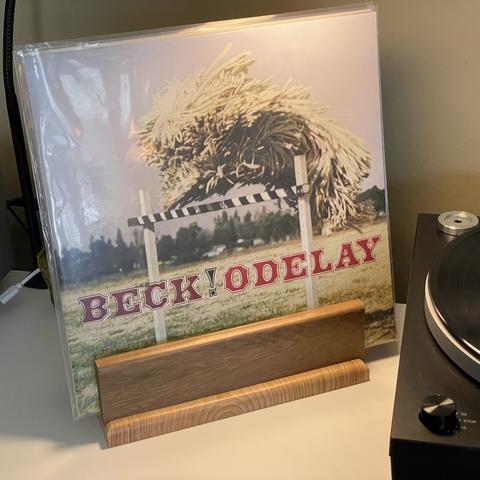 Beck album Odelay! spinning on a turntable with its cover showing a dog jumping over a gate on display.