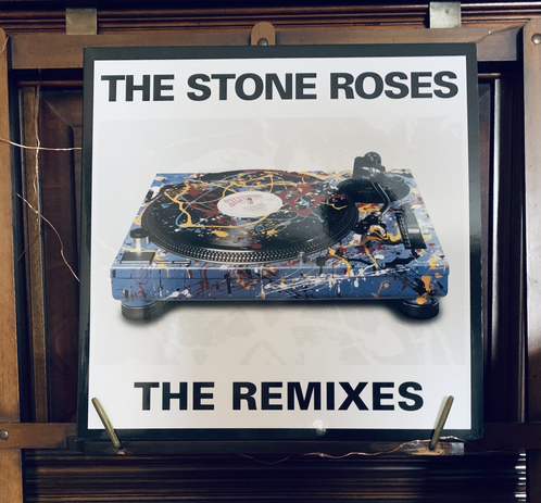 Album is framed on my piano music sheet holder thing. The cover itself is white background with ‘The Stone Roses’ up top, and ‘The Remixes’ at the bottom both in black capitalised font. In the middle is a paint splattered technics record deck in multiple colours of blue, red, yellow and white…a nod to the paint splatter style used on the main cover of the album the remixes are based on, 1989’s self-titled’’The Stone Roses’.