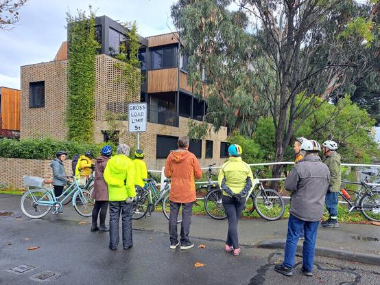 A group of people with bicycles discuss Ruskin, the recently completed 3 storey townhouses in Elwood.