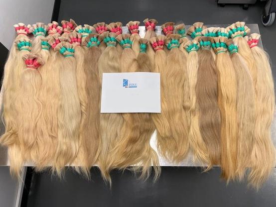 Rund 100 Kilogramm blonde Echthaare liegen aufgereiht auf einem Tisch.
