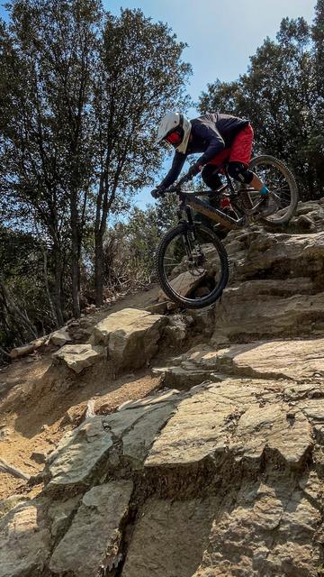Mountainbiker fährt steiles Felsstück runter.