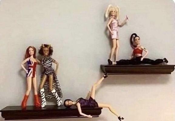 Two small shelves on a wall, upon which dolls of the Spice Girls are displayed in various poses.