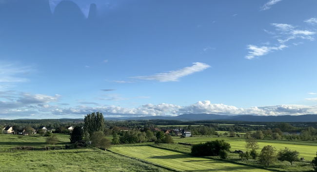 Still from video of geen, rolling hills and farmland passing by from train window.