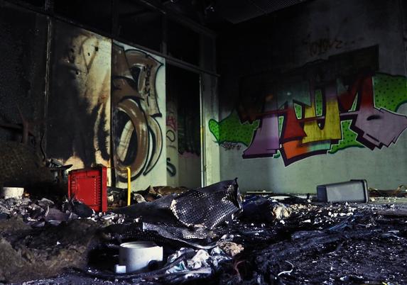Ein Raum voller Müll auf dem Boden, im Hintergrund ein buntes Graffiti
