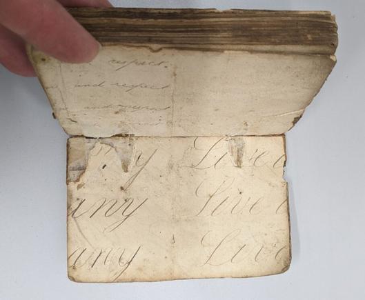 Book open at right board. Cream paper with large scale cursive handwriting.