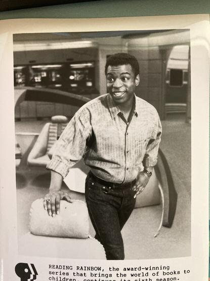 Press photo for Reading Rainbow. Levar Burton stands on the bridge of the Enterprise-D in a behind the scenes photo of Star Trek: The Next Generation.