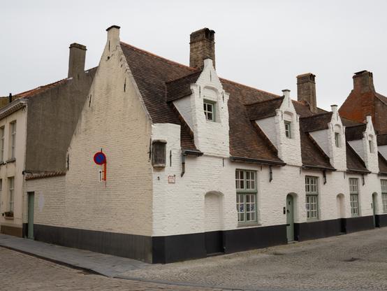 Angular building with multiple dormers set on a corner in Bruges evenly lit in flat cloudy light.