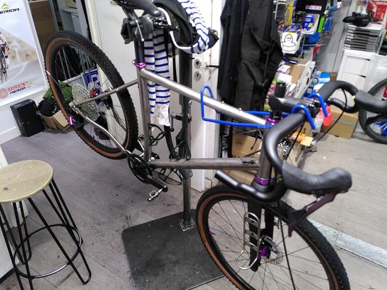 Vélo en titane avec des touches violettes en cours de montage sur un pied d'atelier