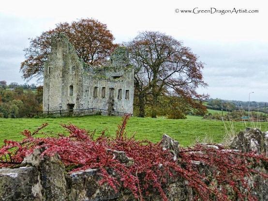 Ruined house surrounded by autumn colored foliage on a green field