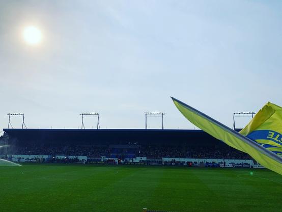 The main stand of USG, with the sun setting begind it begind a light cloud cover. On the side an antifascist USG flag.