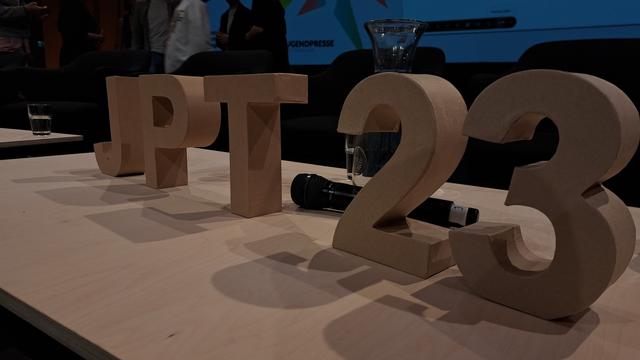 Foto von der Bühne, worauf ein Tisch steht und dort sind die Buchstaben "JPT" und die Ziffern (beides aus Holz) "23" aufgestellt.