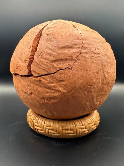 Broken red ochre ball on top of woven bracelet.