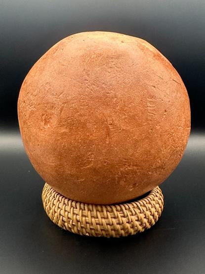 Red ochre ball on top of woven bracelet.