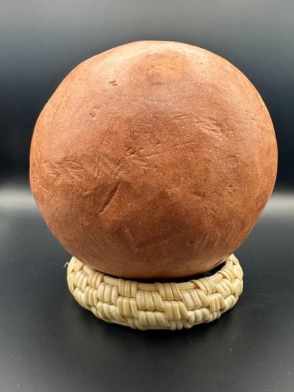 Red ochre ball on top of woven bracelet.