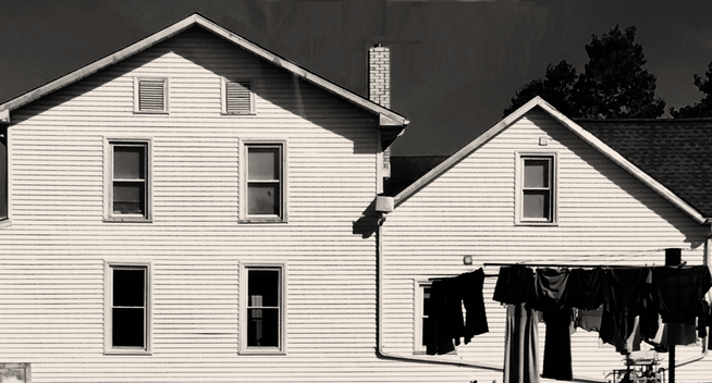 Image of a white Amish farmhouse with clothing hanging out on a line to dry.