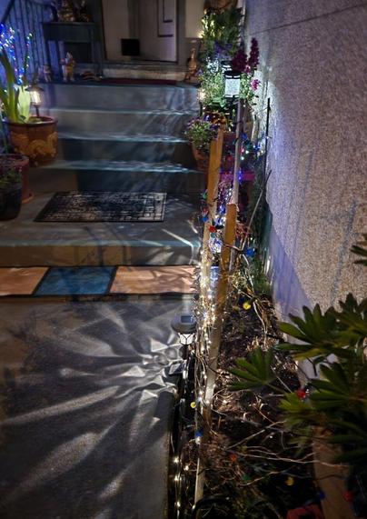 Our front porch gardens in the nighttime. Many potted perennials & garden decorations, with solar lights mixed in.
