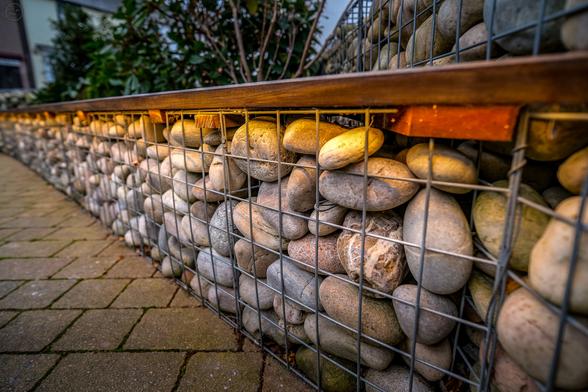 Urban bench seating made of wire mesh filled with large pebbles with a warm glow of under seat lighting