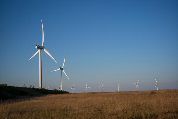 Two windmills fairly close, more on a line in the distance. Grasslands.