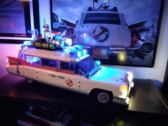 This Lego Ghostbusters Ecto-1 is roughly 19" long and is lit bumper to bumper with LED emergency lights. A photo of the rear-end of the film Ecto-1is offset behind it.