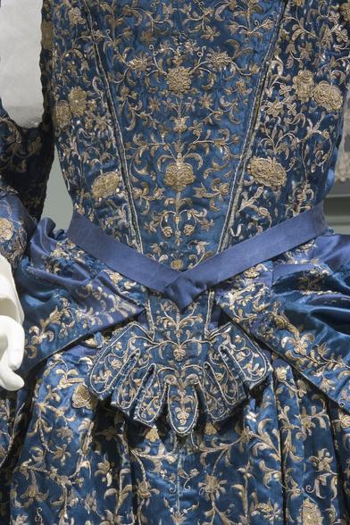 the bodice of an embroidered gown -- the embroidery is gold floral, incredibly intricate, with a border of gold -- the background material is gorgeous blue satin.