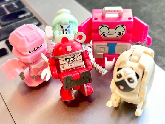 A group of five Botbots, tiny household items that turn into robots (and a pugh??) all looking up towards the camera