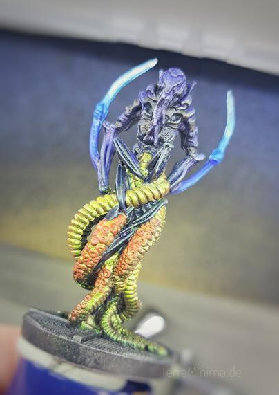 Nahaufnahme einer bemalten Miniatur in Form eines Alien mit Tentakel als Beine.
Die Arme laufen spitz nach oben weg.