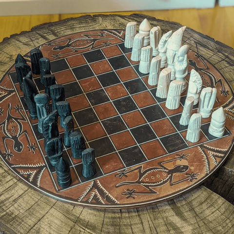 a red, white, and black chess stone chess set. a salamander is carved on the outside.