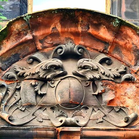 Two beautifully carved dolphinfish on the front of an old red sandstone building.