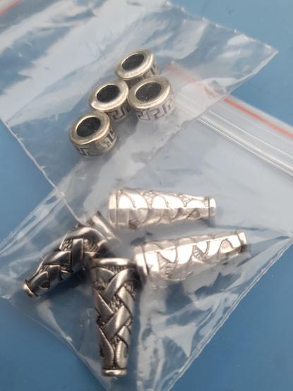 The silver elements: rings with ancient Greek meander gravure and conical tubes with Irish knot design.