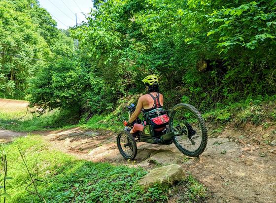 Female adaptive mountain bike rider rolling down a steep rocky hill