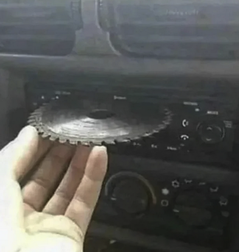 someone inserting a blade of a band saw into a car cd player.