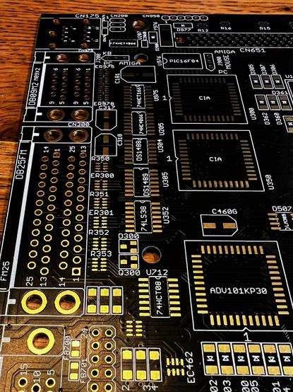 A bare, black Amiga 4000 ATX motherboard, closeup of the rear ports area. It's black and golden and shiny.
