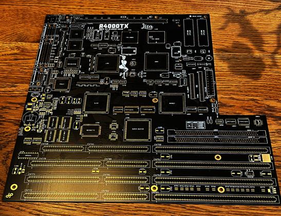 A bare, black Amiga 4000 ATX motherboard on a wooden table, it's new and shiny and has gold accents.
