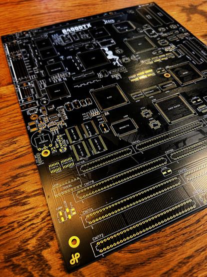 A bare, black Amiga 4000 ATX motherboard, with a holden letter H for the designer Hese in one of the corners.
