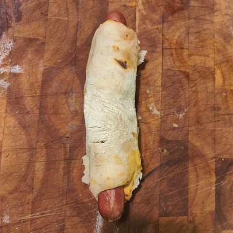 A hot dog rolled in pizza dough and cooked.