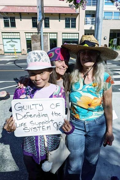 Me holding up a sign that says: Guilty of defending the life support system. With 2 environmental activist friends, at Nanaimo Courthouse.