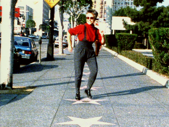 Barbara Hammer, short blond hair, red turtle-neck sweater, grey salopettes (I smell a pun here…) and sunglasses, smiles while tap dancing on Shirley Temple's star. As Tender Fictions explains, Hammer's mother hoped her daughter to be like the child star.