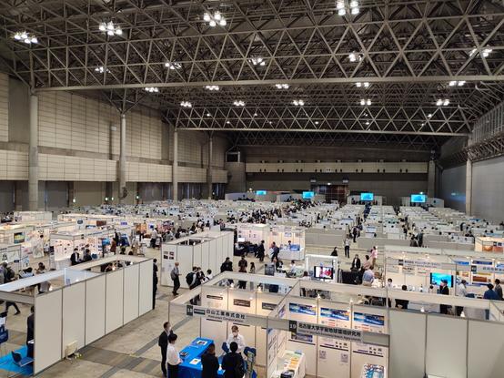 View into a large hall with exhibition booths and poster walls.