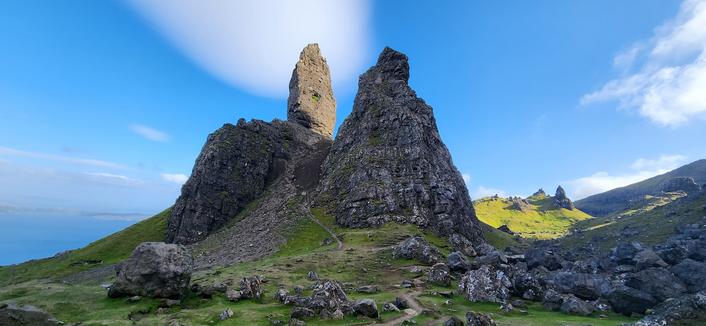 An image looking up towards the Old Man of Storr with shadow around everything but sunlight on the famous rocky outcrop