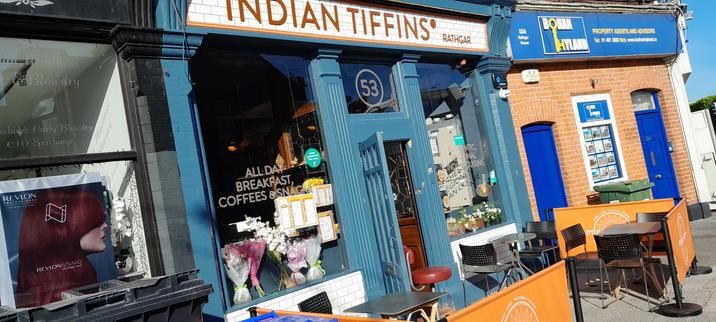 Front of Indian Tiffins restaurant and its sidewalk seating basking in the morning sun.  The day is grand altogether.