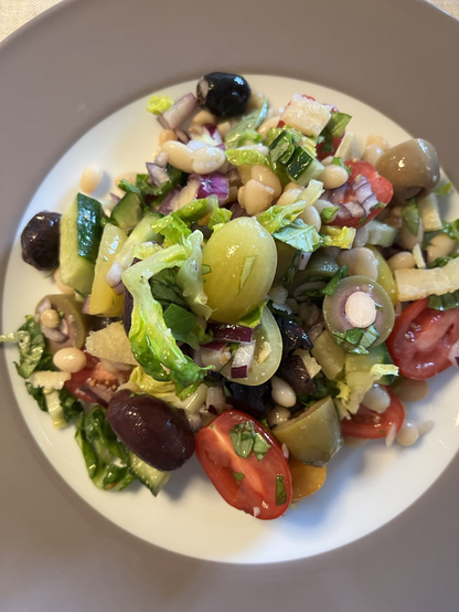 Salat af marinerede hvide bønner, hjertesalat, agurk, rødløg, oliven, basilikum, tomater, pinjekerner og parmesan.