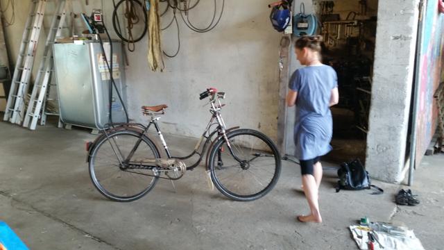 Ein altes Hollandrad, eine Frau im blauen Kleid und Fahrradwerkzeug