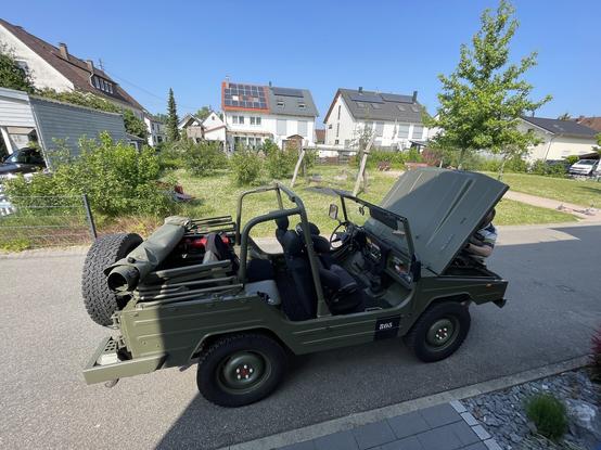 Ein klassisches Militärfahrzeug mit offener Motorhaube. Das Cabriodach ist offen.