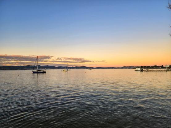 Spot pallete sunset on the lightly rippled water, a couple of boats and a jetty lazing about.
