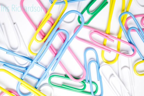 Colorful Paperclips - A colorful macro photograph of paperclibs on a white background. The first patent for a bent wire paperclip was created in 1867, given to Samuel B. Fay. Its origianl use was intended to hold tickets to fabric without damaging the fabric. The simple three-bend oval paperclip we know today was created by the Gem Manufacturing Company in Britain, and since there was no patent for it, historians have to guess when it was made. They suspect it was created in 1870, and it was introduced to the Americas around 1892. Paperclips were even used as a symbol of rebellion, briefly during World War II. Source: https://blogs.bellevue.edu/library/index.php/2020/05/national-paperclip-day/ 

Artist Iris Richardson, gallery ArtHero and Pictorem