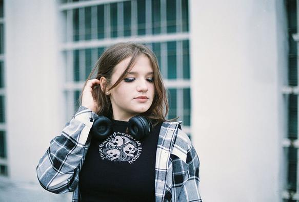 Portrait of a girl looking to the right and fixing her hair. Photo has slightly teal tint since the film it was shot on is very old.